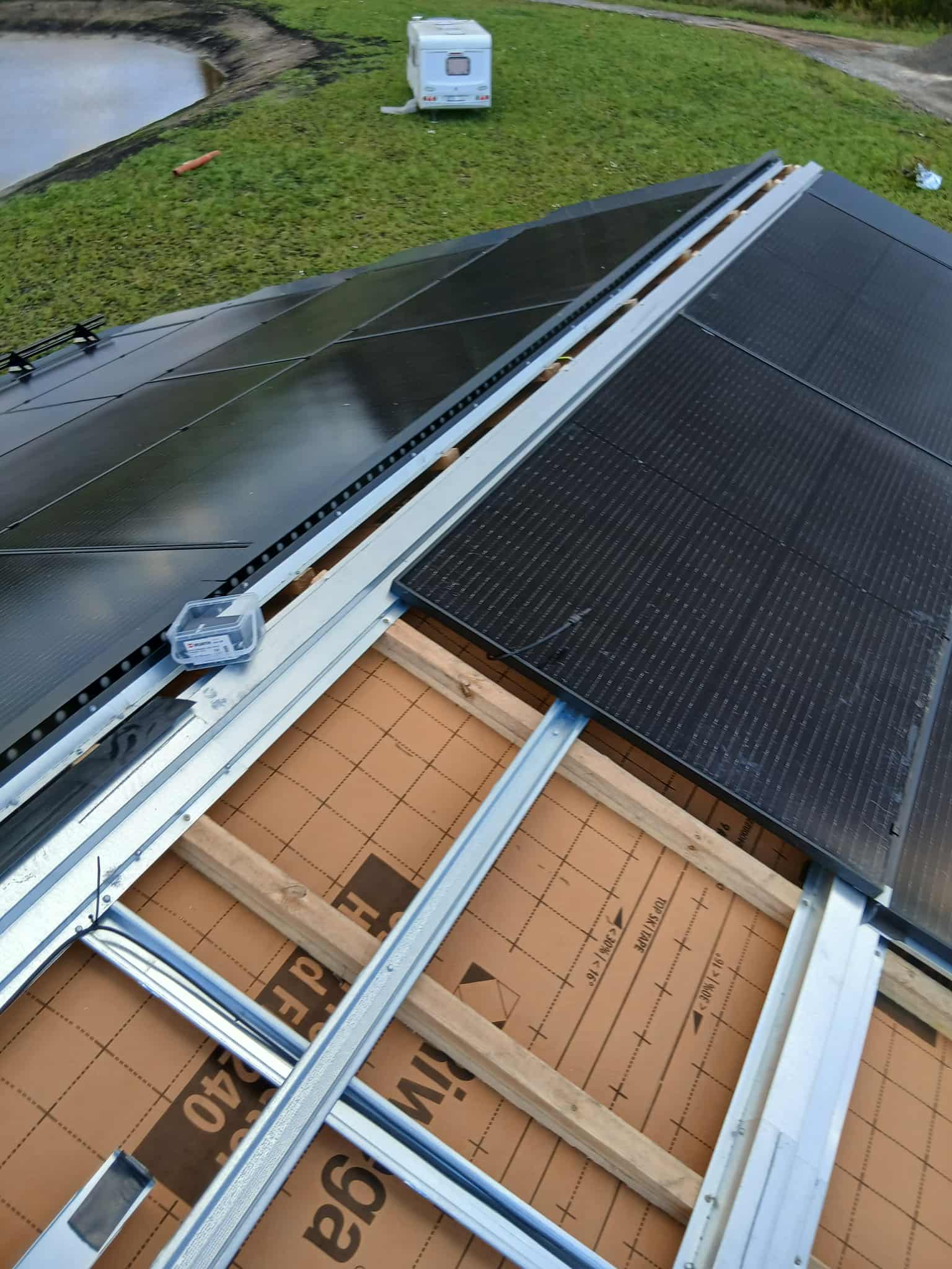 HolaRoof installation showing solar panel with metal rails and green landscape